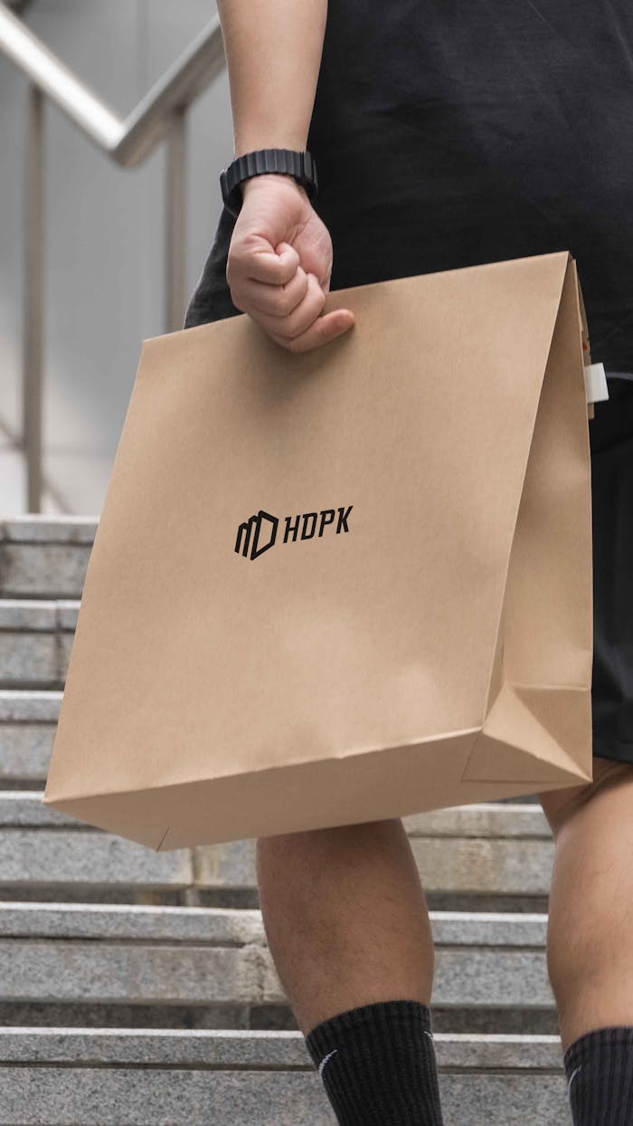 Close-up of an eco-friendly paper bag held by a person on a staircase, promoting sustainability.